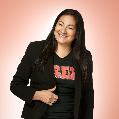 Picture of Rosanna Deerchild, smiling, with a faded orange, flat background.